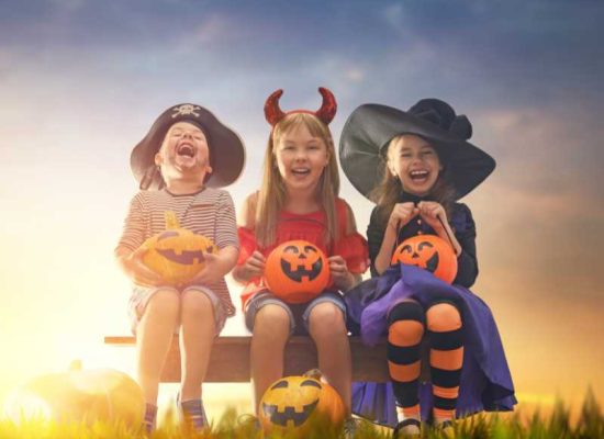 Three children in Halloween costumes sitting on a bench, promoting a healthy Halloween in 2022.